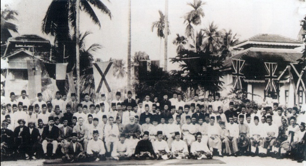 Black and white image of large group of men sitting or standing. 