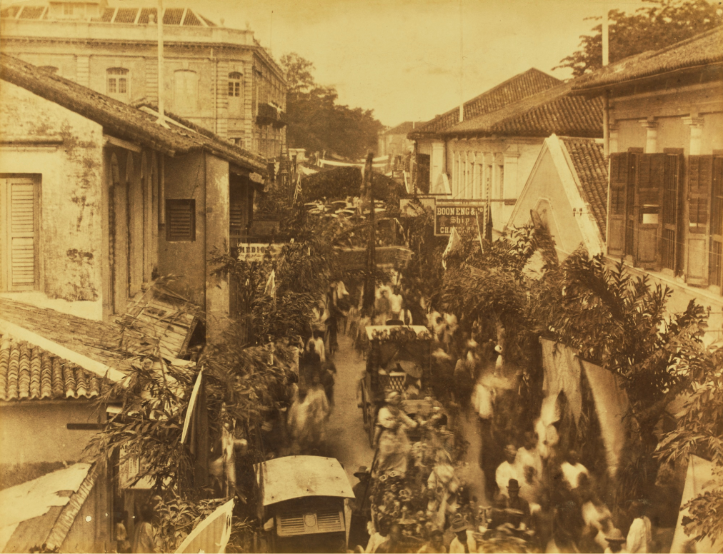 Sepia photo of a parade passing by Kuan Yin Temple.