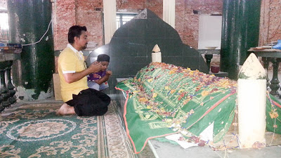 A father and child offering prayers inside the mausoleum.