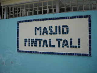 A blue and white tiled sign that reads 'Masjid Pintal Tali'.