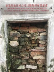 A bricked-up secret passage with a sign above it explaining its history.