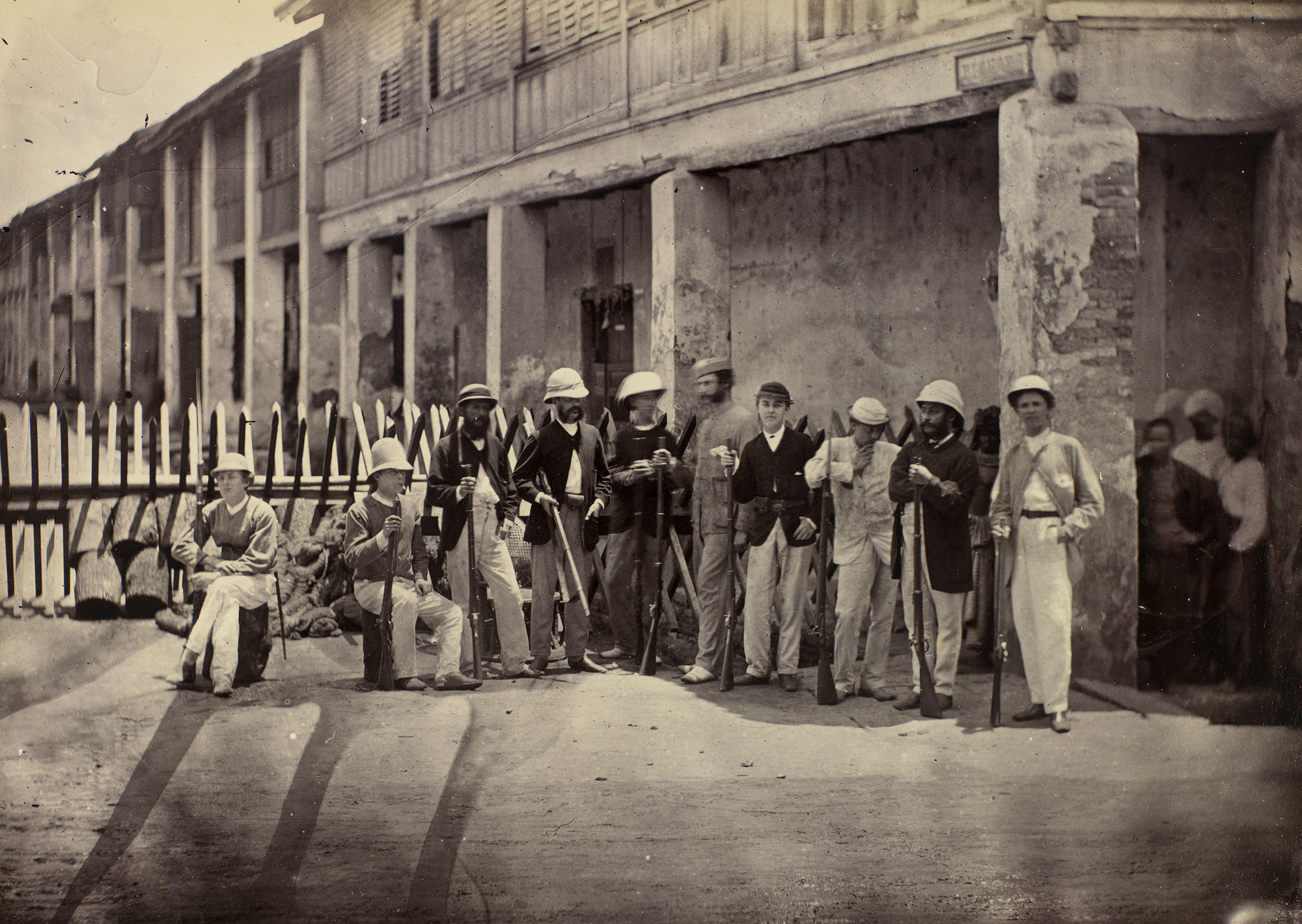 Black and white photo of soldiers, mostly European, at a barricade.