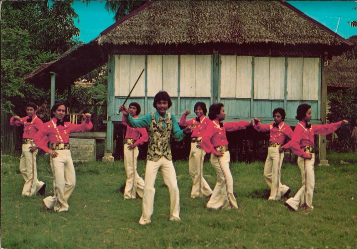 Colour photo of group in costumes performing in front of a small building at Wembly Amusement Park 