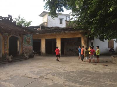 A hall with some children gathered in the courtyard outside.