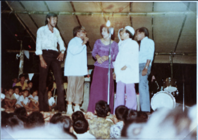 Blurred picture of group performing over a seated audience. 