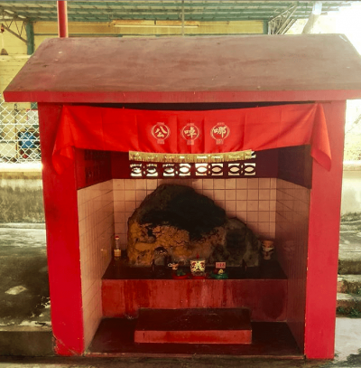 A red and white shrine with a stone at the centre.