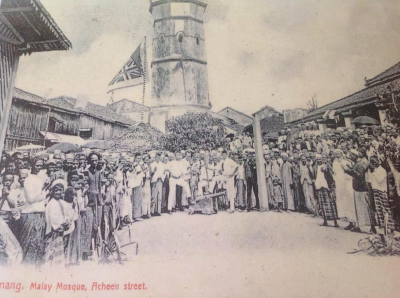 A black-and-white photo of a large group of people gathered in front of the mosque.