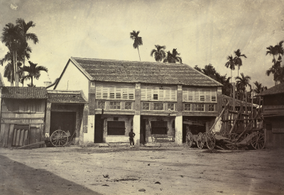 A black and white photo of a building with a barricade built across the street next to it.