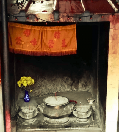 A stony shrine with a blue vase holding yellow flowers.