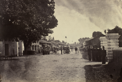 Soldiers gathering in the street with large guns on wheels.