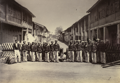 Black and white photo of soldiers posing for a photograph at a street barricade.