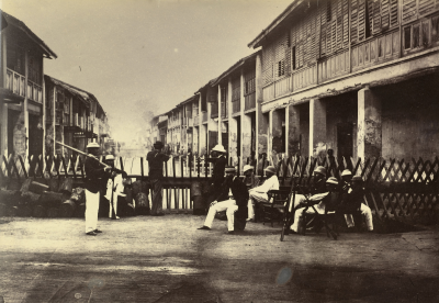 Black and white photo of soldiers sitting down behind a barricade.