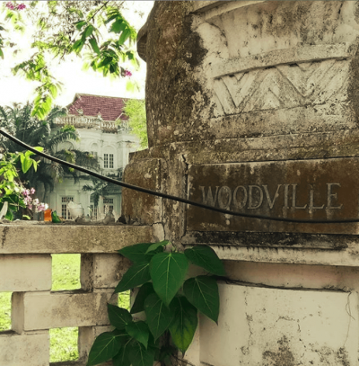 The sign on the property entrance to Woodville, with the house seen over the fence in the background.